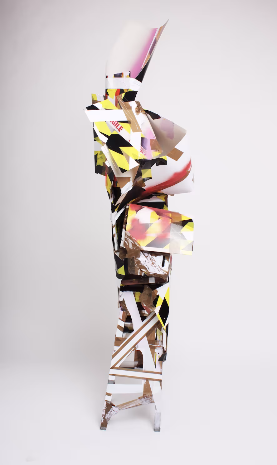 Escaping the Confines (2020) Reclaimed plastic, reclaimed stool, packaging tape, cardboard, spray paint and paint. 190 x 30 x 30 cm